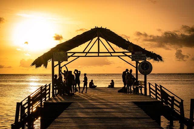 Photo by Kenrick Baksh: https://www.pexels.com/photo/silhouette-of-people-standing-on-a-thatched-roof-jetty-during-sunset-5376665/